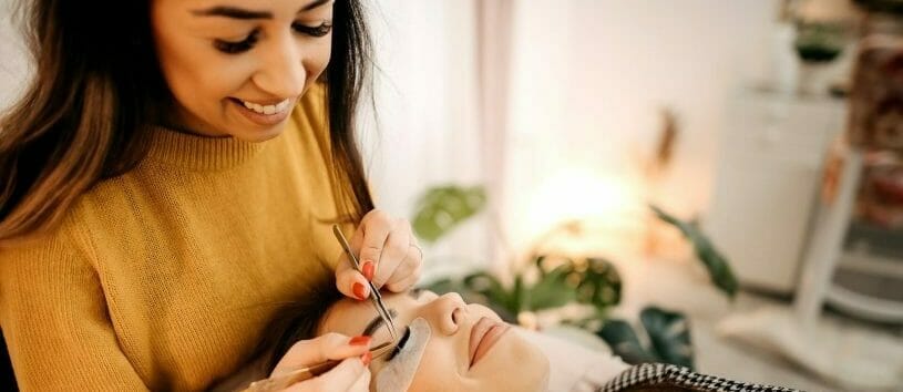Eyelash Extension Specialist applying lash extensions to a female client.